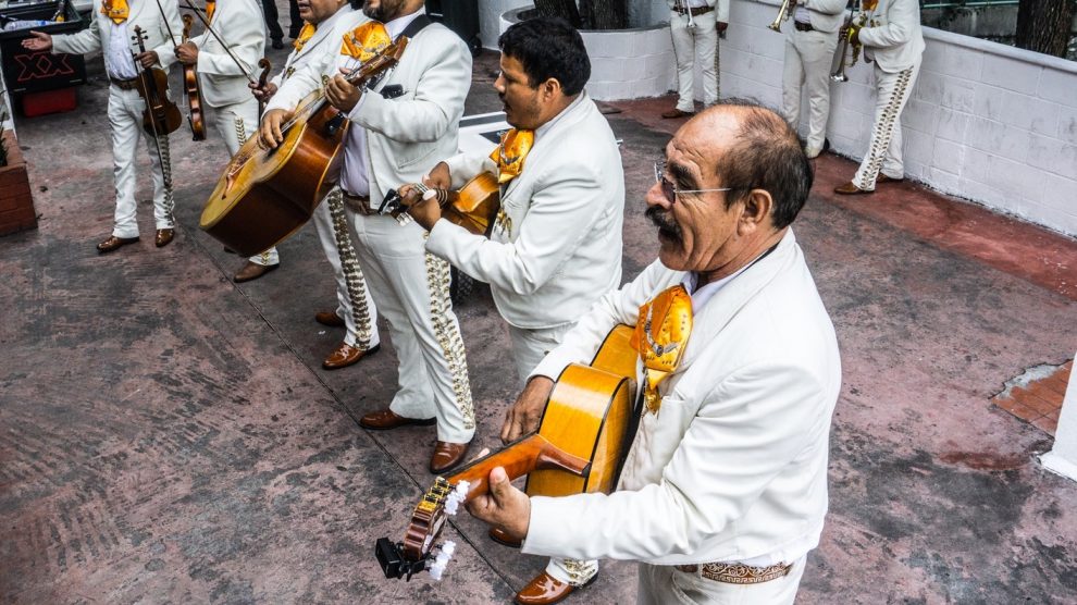 A Mariachi band in traditional garb with guitars and violins.